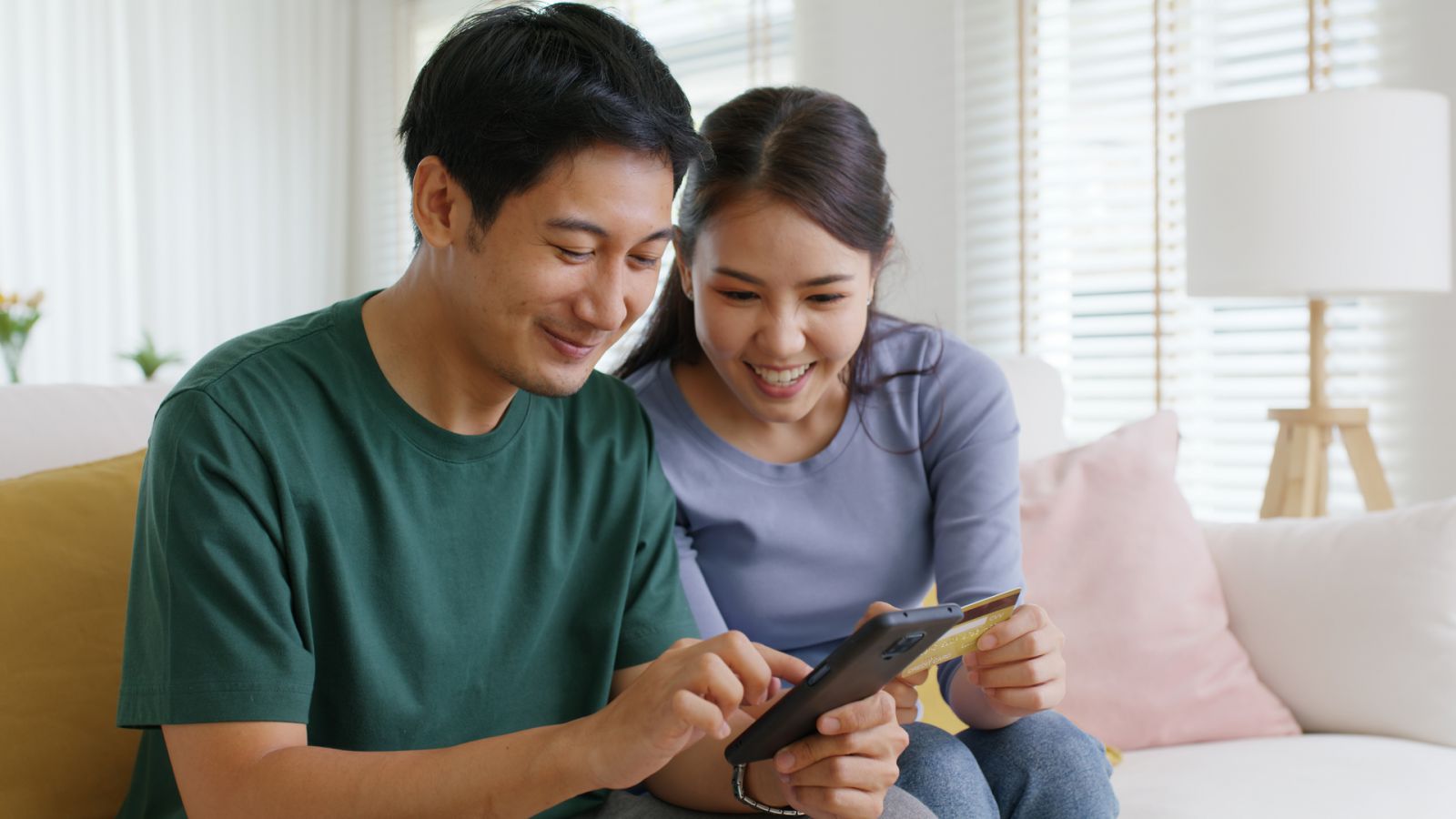 A man and woman smile as they make an online purchase.